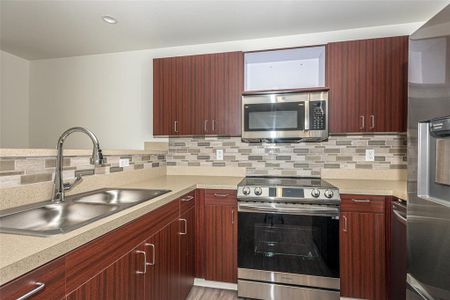 Kitchen featuring kitchen peninsula, stainless steel appliances, tasteful backsplash, and sink