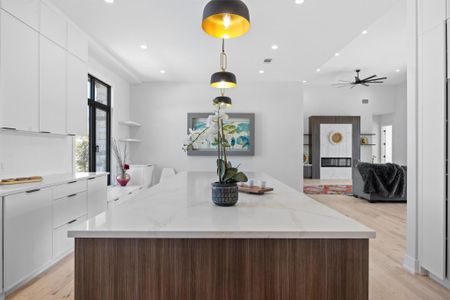 Kitchen featuring a ceiling fan, white cabinets, light wood-style floors, modern cabinets, and a center island