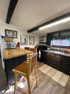 Kitchen featuring beam ceiling, gas range, butcher block counters, and dark wood-style flooring