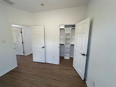 Bedroom with a spacious closet and dark wood-type flooring