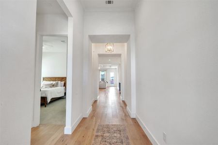 Corridor with ornamental molding and light wood-type flooring