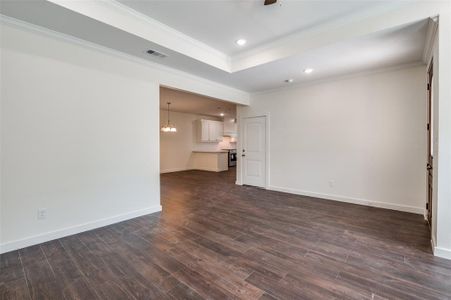 Unfurnished living room featuring crown molding and dark hardwood / wood-style flooring