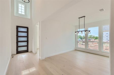 Foyer featuring a chandelier, a towering ceiling, and light hardwood / wood-style flooring