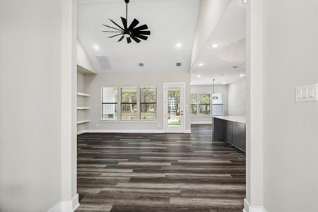 Unfurnished living room with dark hardwood / wood-style flooring, built in features, high vaulted ceiling, and a wealth of natural light