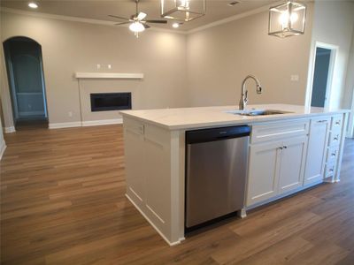 Kitchen with dark hardwood / wood-style flooring, pendant lighting, dishwasher, a kitchen island with sink, and white cabinetry