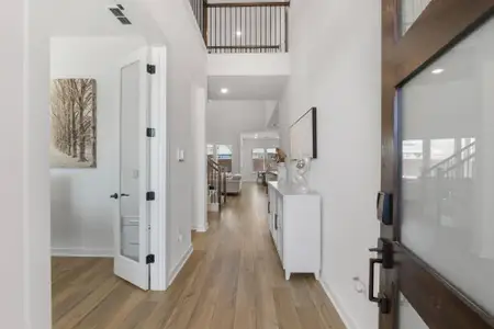 Foyer entrance featuring visible vents, baseboards, a towering ceiling, and light wood finished floors