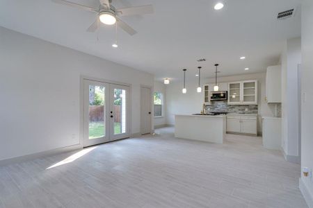 Kitchen with decorative light fixtures, white cabinetry, tasteful backsplash, a kitchen island, and ceiling fan