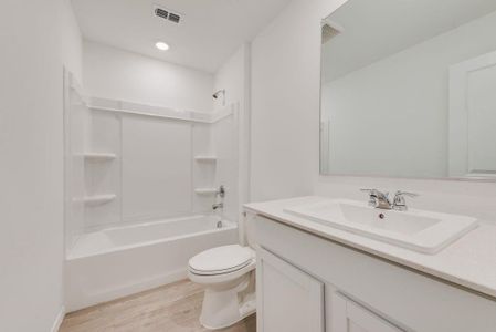 Full bathroom with bathtub / shower combination, toilet, wood finished floors, vanity, and visible vents