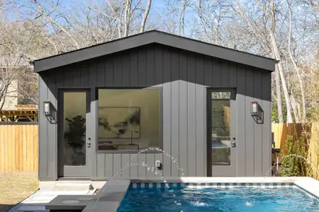 View of pool house featuring a swimming pool and fence