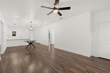 Unfurnished living room featuring dark hardwood / wood-style floors, sink, and ceiling fan with notable chandelier