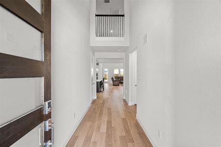 Corridor with light hardwood / wood-style flooring and a towering ceiling