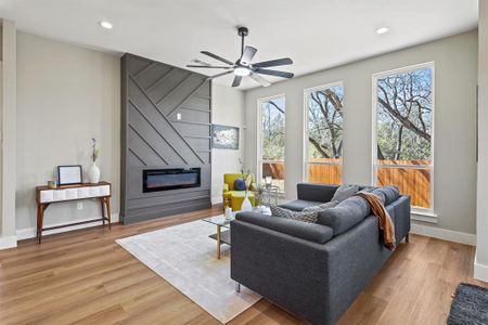 Living area with recessed lighting, a large fireplace, light wood-style flooring, and baseboards