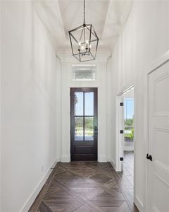 Doorway with a wealth of natural light, a high ceiling, an inviting chandelier, and dark parquet floors