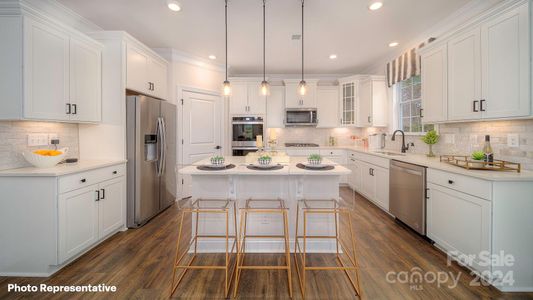 Beautiful open kitchen with quartz countertops, double wall ovens, gas cooktop and ceramic backsplash.