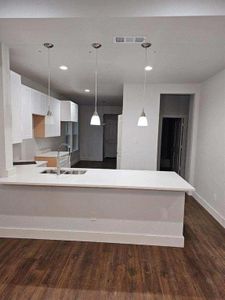 Kitchen featuring sink, hanging light fixtures, kitchen peninsula, and dark wood-type flooring