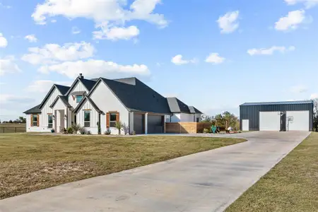 View of front of property with a garage, an outdoor structure, and a front lawn