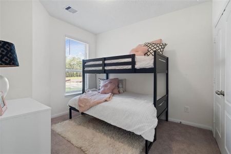 Secondary bedroom features plush carpet, high ceilings, ample closet space, and a large window with privacy blinds.