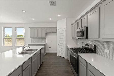 Kitchen with gray cabinetry, sink, hanging light fixtures, dark hardwood / wood-style flooring, and appliances with stainless steel finishes