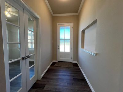 Entryway featuring dark hardwood / wood-style floors, ornamental molding, and french doors