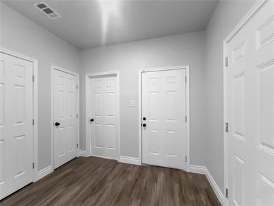 Unfurnished bedroom with dark hardwood / wood-style flooring and two closets