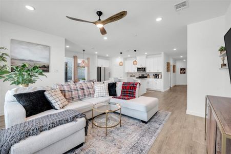 Living room with ceiling fan, sink, and light hardwood / wood-style flooring