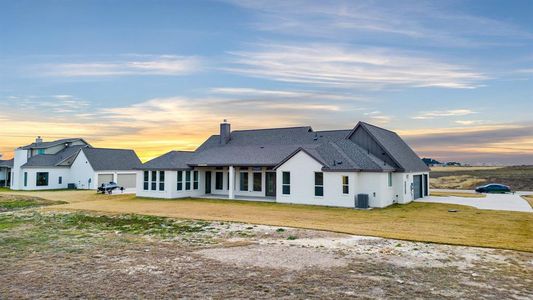 Back house at dusk featuring a lawn and central AC