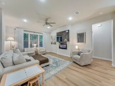 Living room featuring plenty of natural light, ceiling fan, high ceilings, and a fireplace