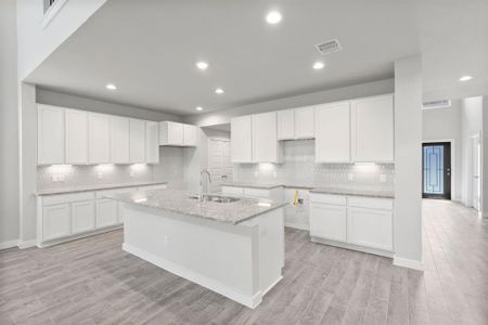 The kitchen is a culinary haven, featuring granite countertops, a tile backsplash, stainless steel appliances, 42” upper cabinets, and undercabinet lighting. Sample photo of completed home with similar floor plan. As-built interior colors and selections may vary.