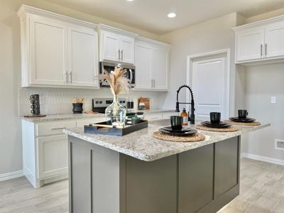 Kitchen with white cabinetry, stainless steel appliances, and an island with sink