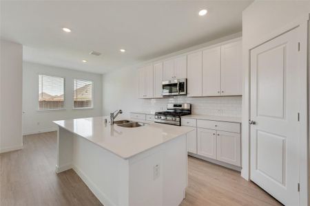 Kitchen with white cabinets, a kitchen island with sink, stainless steel appliances, and sink