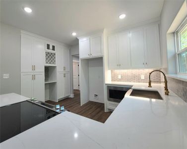 Kitchen featuring sink, light stone counters, decorative backsplash, dark hardwood / wood-style floors, and white cabinets