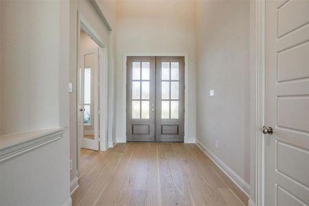 Foyer entrance with light hardwood / wood-style floors and french doors