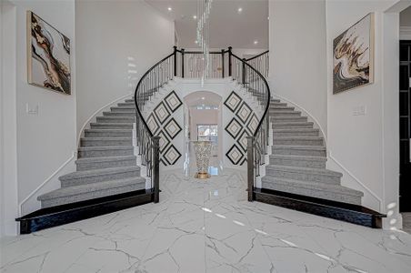 Step inside and be captivated by a dramatic entryway featuring a double staircase with wrought iron railings, an impressive rotunda ceiling, and tastefully designed wall paneling. This awe-inspiring introduction sets the tone for the home’s luxurious interiors.