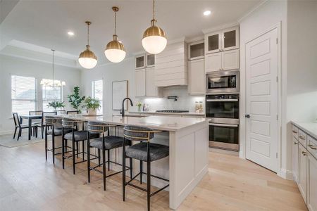 Kitchen featuring custom cabinetry to the ceiling, light hardwood floors, large island with Quartzite countertops, and beautiful hardware.