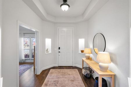 Entryway with dark hardwood / wood-style floors and a tray ceiling