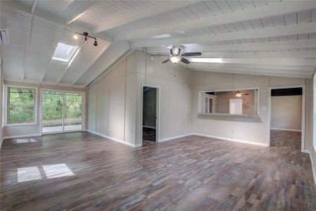 Unfurnished living room with wood ceiling, dark wood-type flooring, vaulted ceiling with skylight, and ceiling fan