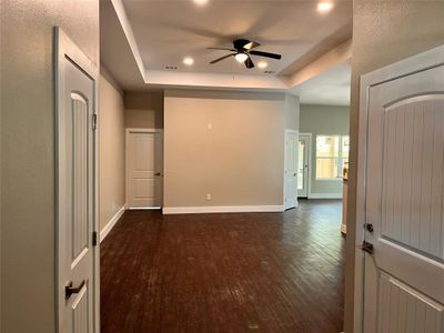 Empty room featuring ceiling fan, dark hardwood / wood-style floors, and a tray ceiling