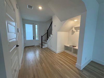 Foyer entrance featuring stairway, baseboards, visible vents, and wood finished floors