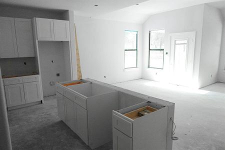 Kitchen with vaulted ceiling, white cabinets, and a kitchen island