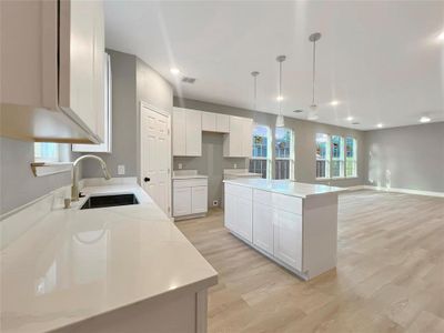 Kitchen featuring sink, pendant lighting, light hardwood / wood-style flooring, white cabinets, and a center island