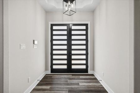 Entryway featuring french doors, dark wood-type flooring, and an inviting chandelier