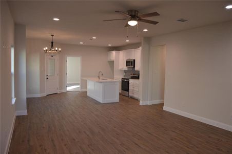 Kitchen with appliances with stainless steel finishes, a kitchen island with sink, sink, decorative light fixtures, and white cabinets