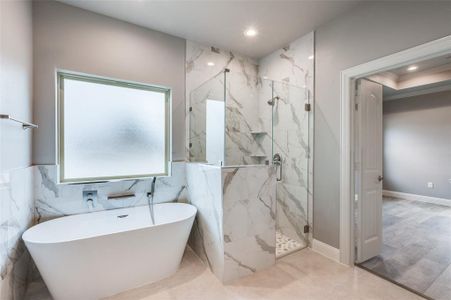 Bathroom featuring ornamental molding, separate shower and tub, and tile walls