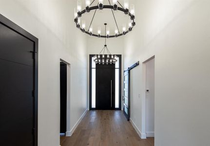 Foyer with a high ceiling, a12ft Custom door, white oak hardwoods throughout , and a chandelier