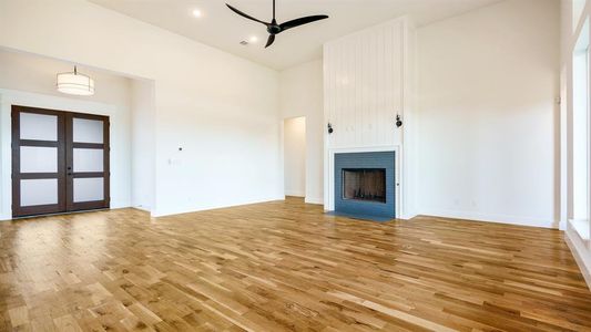 Unfurnished living room with french doors, a high ceiling, and light wood-type flooring