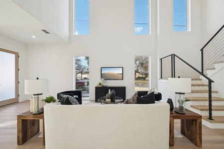 Living room with a high ceiling, plenty of natural light, and light hardwood / wood-style flooring