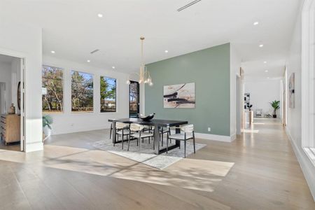 Dining room with light wood-type flooring and a notable chandelier