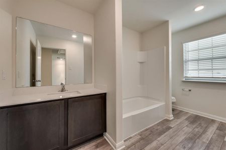 Full bathroom featuring hardwood / wood-style flooring, vanity, shower / bathtub combination, and toilet