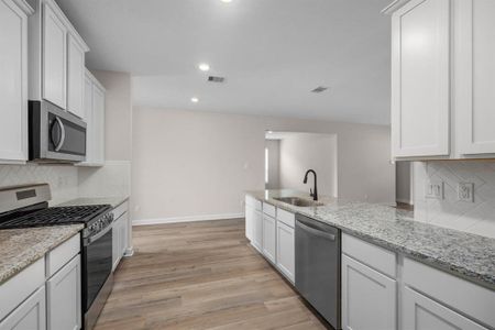 This spacious kitchen is a chef's dream. It has granite countertops, a full suite of stainless steel appliances, and a view of the family room. This open kitchen has a breakfast bar for casual dining and easy entertaining.