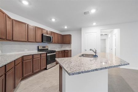 Another view of this beautiful kitchen showcasing the stainless steel Whirlpool gas range and microwave, and the granite countertop with modern tile backsplash.